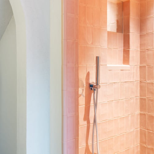 Die Wandgestaltung in den Bädern erfolgte durch eine einzigartige Kombination von rötlich farbigen Fliesen und hellem, natürlichen Lehm-Designputz. Der YOSIMA Lehm-Designputz wurde in den Farbtönen WE0 und Kolumba-Grau verwendet.