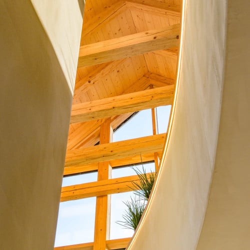 Die Holzkonstruktion ist kombiniert mit hohen, glatten Lehmwänden, welche mit dem YOSIMA Lehm-Designputz gestaltet wurden. Das gesamte Haus, bis auf das Unter- und Gartengeschoss, wurde in dem Farbton Kolumba-Grau gestaltet